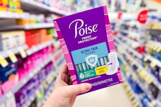 person holding a package of poise pads in an aisle