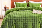 Green duvet cover and pillow cases displayed on bed in a room setting