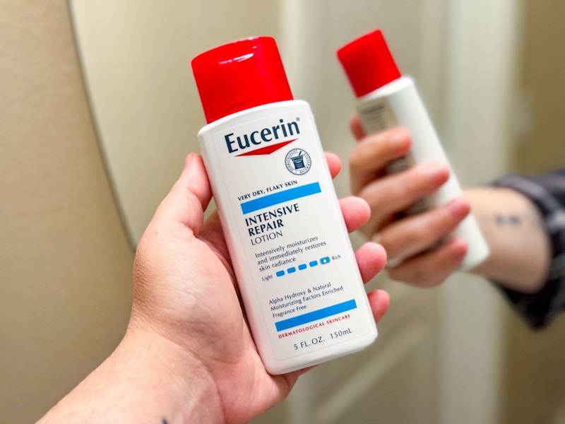 person holding eucerin lotion in front of a mirror
