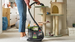 a person using a pet cleaner on a cat tower