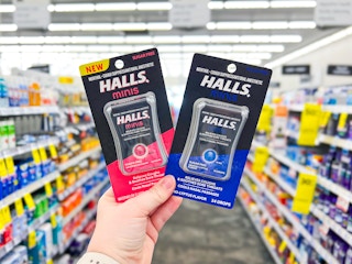 hand holding two packs of halls minis cough drops