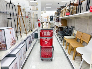a target cart parked in the furniture aisle with lamps and chairs and other furniture items on shelves