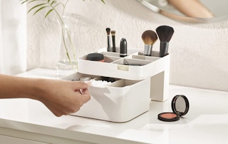 Beige makeup organizer on a desk with someone pulling out a drawer