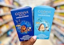 hand holding two Godiva chocolate dome boxes in aisle