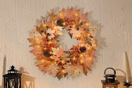 B0F93KSNMP fall wreath 22 in with lights, pinecones, leaves on a beige textured wall