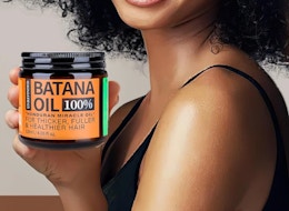 a person holding a jar of batana hair oil 