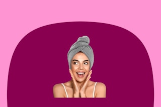 A woman puts her hands to her cheeks in surprise and joy. She is wearing the grey microfiber hair towel with button.