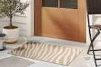 Close up of a lifestyle image shot featuring a striped Threshold area rug in front of rdoor