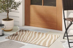 Close up of a lifestyle image shot featuring a striped Threshold area rug in front of rdoor