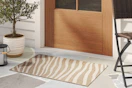 Close up of a lifestyle image shot featuring a striped Threshold area rug in front of rdoor