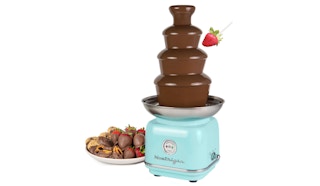 a plate of strawberries next to a retro chocolate fondue fountain