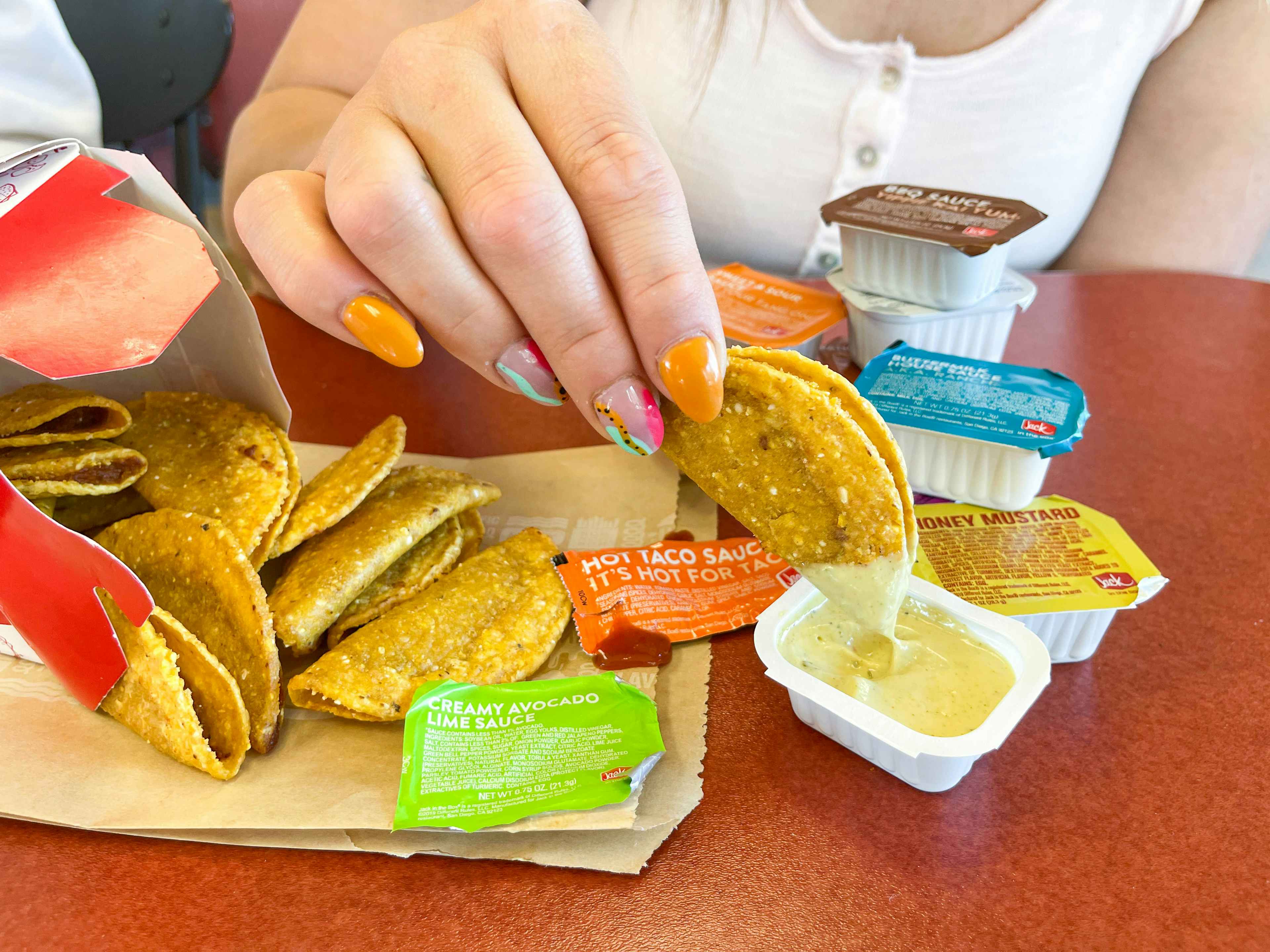 a person dipping mini tacos into sauce