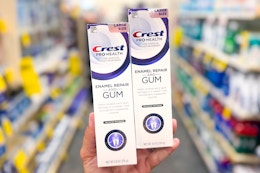 hand holding two crest gum toothpastes