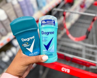 person holding two Degree deodorants in front of shopping cart