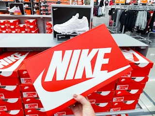 A person's hand taking a box of Nike shoes from a shelf.