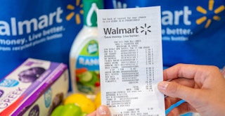 someone holding a Walmart receipt in front of their groceries on a table