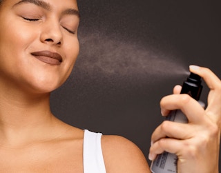 Woman spraying her face with Smashbox setting spray.