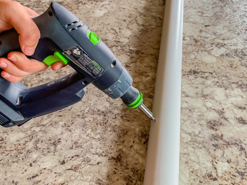 a person drilling holes into a PVC pipe