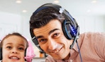 a person wearing a gaming headset next to a little kid