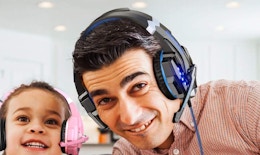 a person wearing a gaming headset next to a little kid