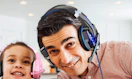 a person wearing a gaming headset next to a little kid