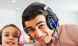 a person wearing a gaming headset next to a little kid