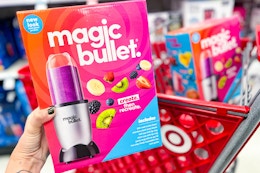 hand holding a magic bullet blender set in front of a target shelf