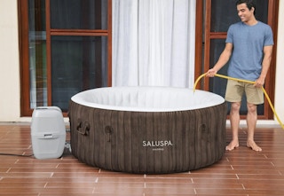 person filling up an inflatable hot tub with water