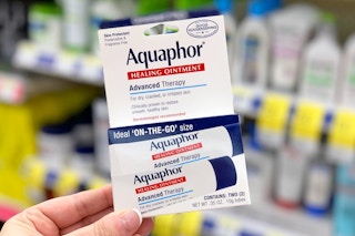 a hand holding a pack of Aquaphor tubes