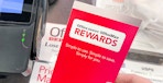 Someone holding an Office Depot rewards pamphlet at the checkout counter