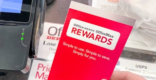 Someone holding an Office Depot rewards pamphlet at the checkout counter