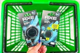 hand holding axe car air fresheners above green shopping basket