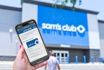 hand holding up a phone with sams club membership outside of store