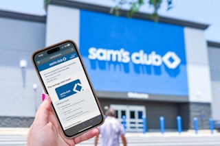 hand holding up a phone with sams club membership outside of store