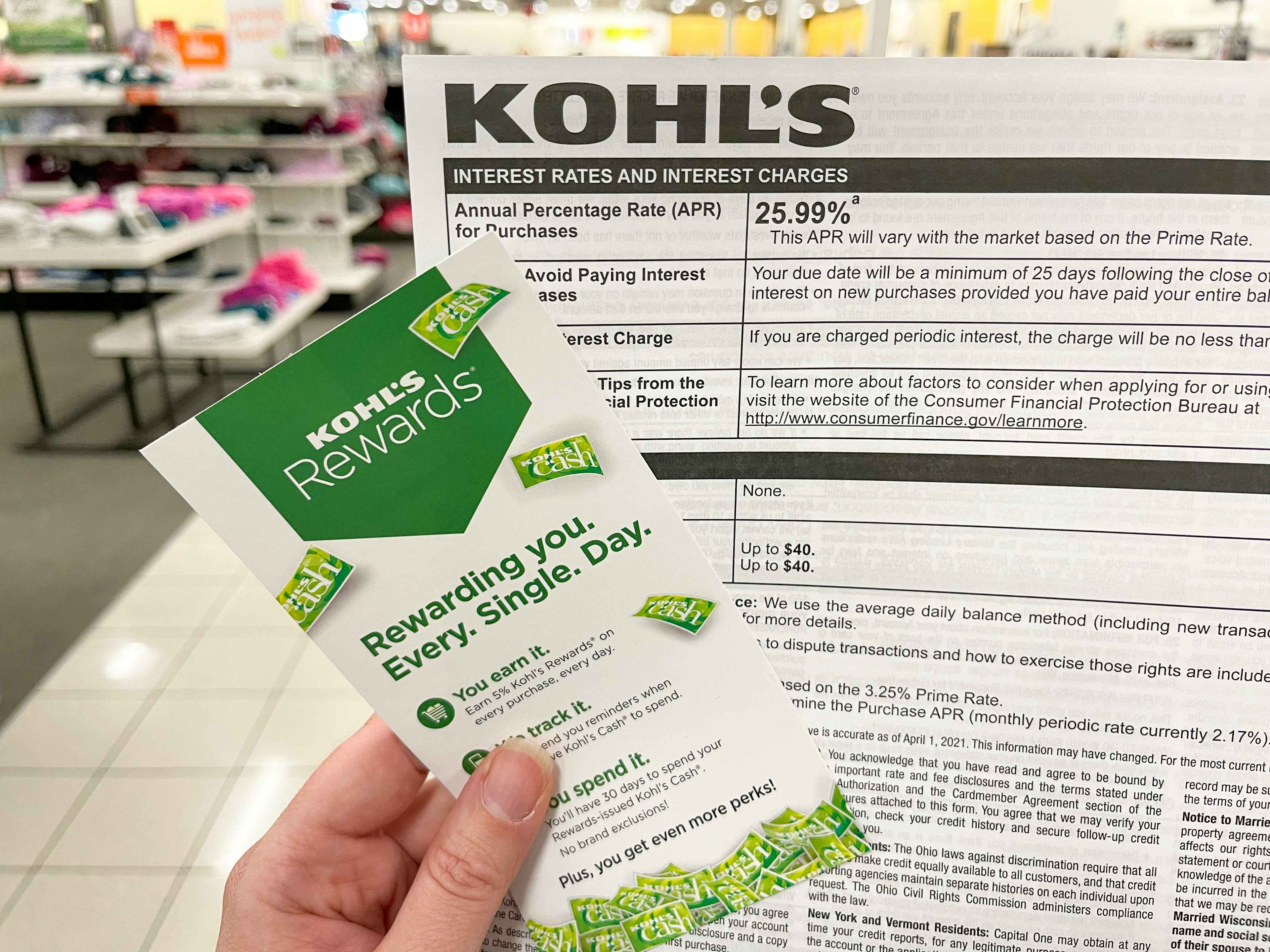 A kohls rewards pamphlet held with a Kohls credit card info sheet
