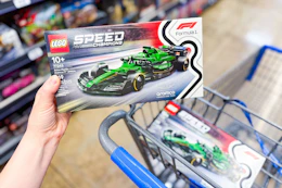person holding a lego speed champions aston martin car building set over a cart