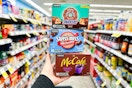 person holding 3 boxes of kcups in an aisle