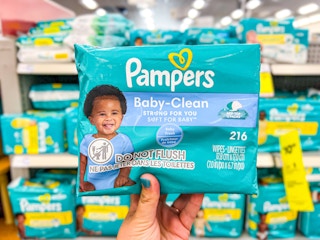 hand holding a pack of pampers baby clean baby wipes