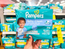 hand holding a pack of pampers baby clean baby wipes
