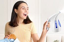 Woman holding portable handheld clothes steamer. B07HF3X6Y4