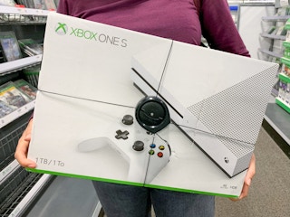 A woman holding an xbox one gaming system at best buy