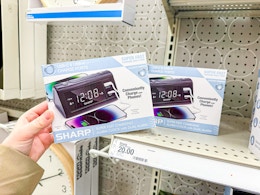 hand holding a sharp dual alarm clock in front of a target shelf