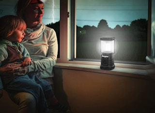 A woman and child sitting at a window with a lantern