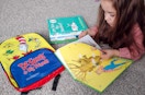 A child laying on the floor reading The Big Honey Hunt next to some more Dr. Seuss books and a Dr. Seuss backpack.