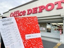 hand holding office depot composition notebook and a receipt in front of office depot store