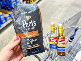 hand holding peets coffee and torani syrup in walmart cart