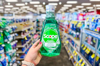 person holding a bottle of scope mouthwash in an aisle