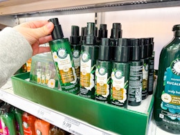 hand grabbing a bottle of Herbal Essences hair product off the shelf
