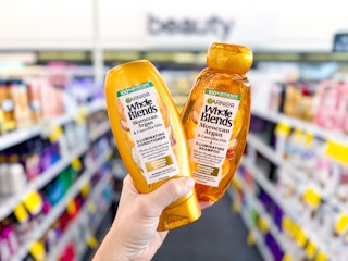 hand holding two bottles of garnier whole blends shampoo and conditioner