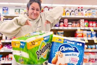 person standing over bounty and charmin paper products pointing at them
